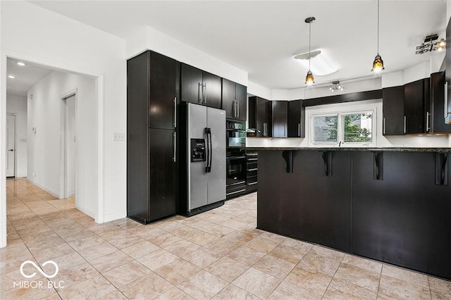 kitchen with stainless steel fridge, kitchen peninsula, decorative light fixtures, black double oven, and a breakfast bar