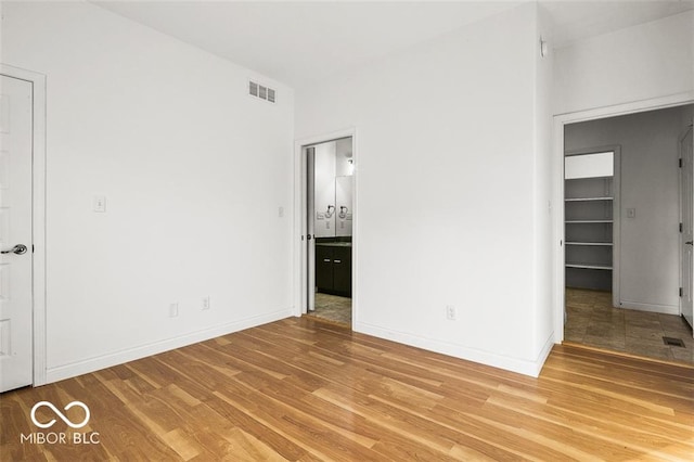 unfurnished bedroom featuring light hardwood / wood-style flooring and connected bathroom