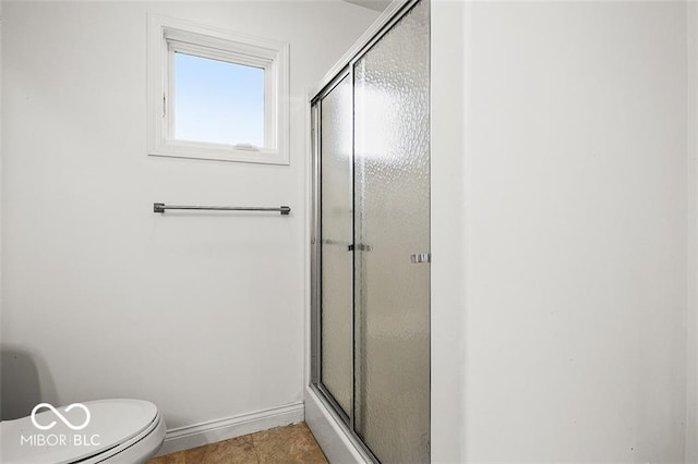 bathroom with tile patterned flooring, a shower with door, and toilet