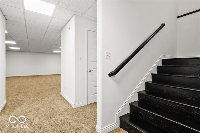 stairs with carpet floors and a paneled ceiling