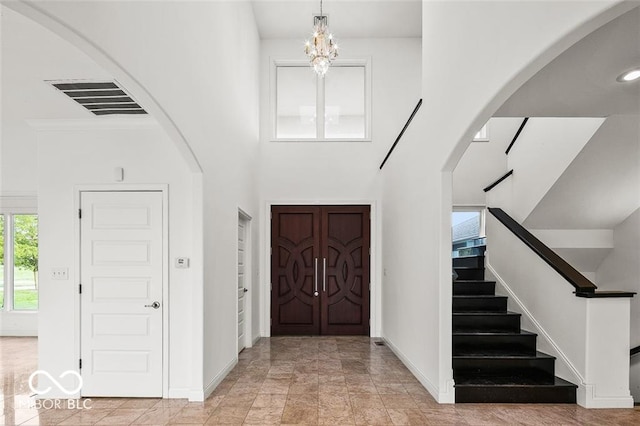 entryway featuring a towering ceiling and a notable chandelier