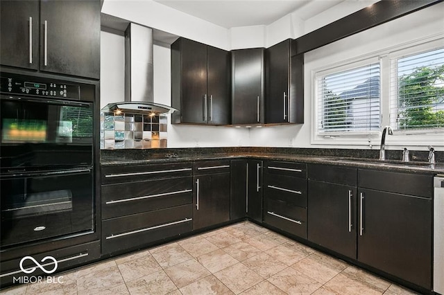 kitchen with backsplash, wall chimney exhaust hood, dark stone counters, double oven, and sink