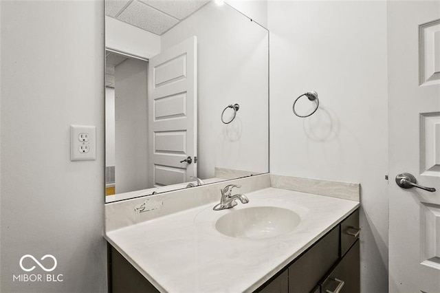 bathroom with a paneled ceiling and vanity