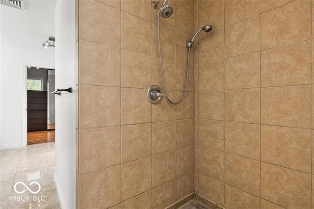 bathroom with tiled shower and tile patterned flooring