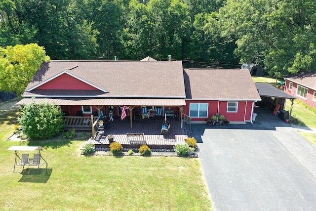 exterior space with aphalt driveway, an attached carport, a front lawn, and a shingled roof