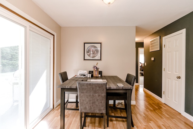 dining room with light wood-type flooring and a healthy amount of sunlight