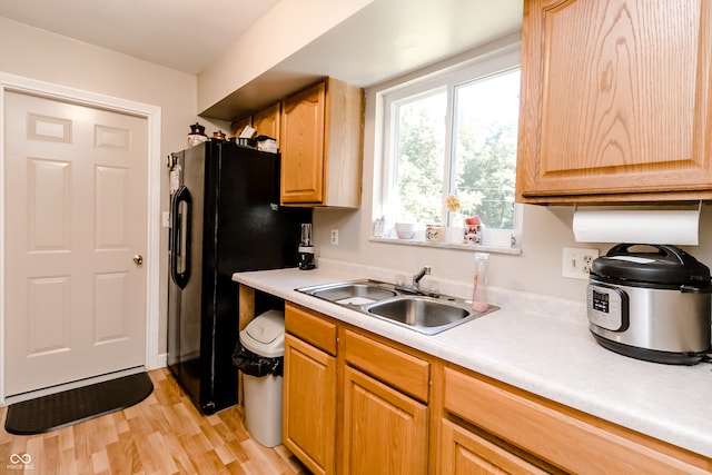 kitchen with sink, black refrigerator, and light hardwood / wood-style flooring