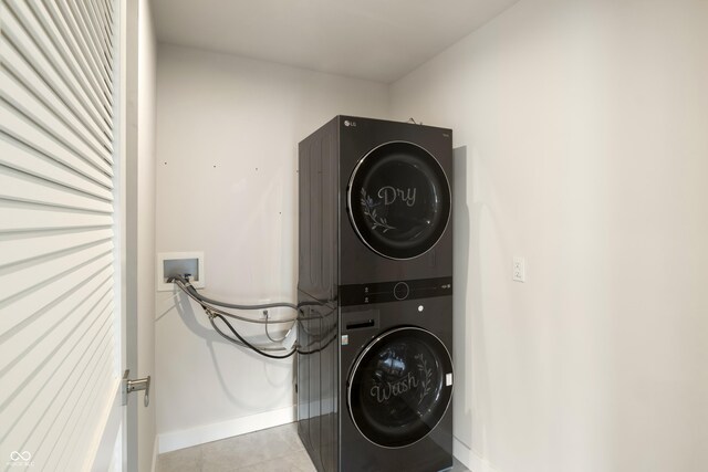 laundry area with light tile patterned flooring and stacked washer and clothes dryer