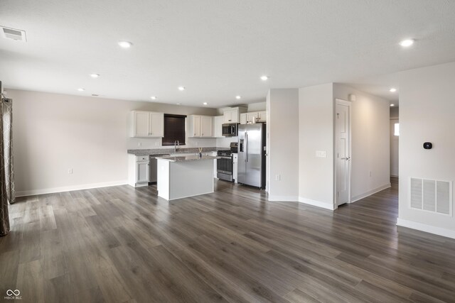 kitchen with sink, dark hardwood / wood-style flooring, appliances with stainless steel finishes, a kitchen island, and white cabinets