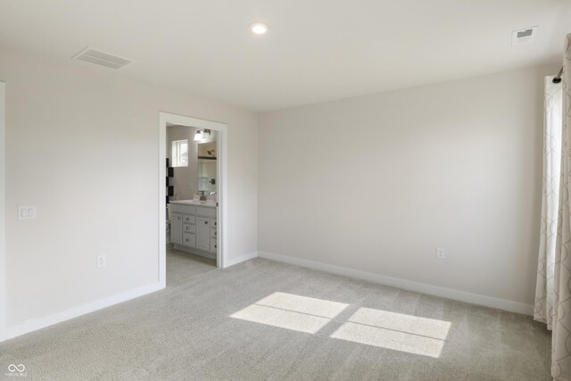 unfurnished bedroom featuring sink, connected bathroom, and light carpet