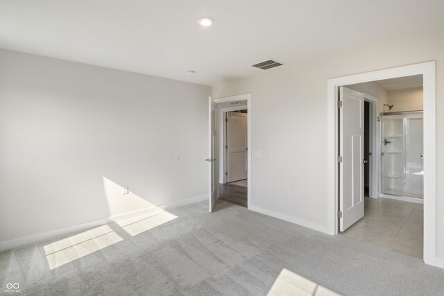 unfurnished bedroom with light colored carpet and ensuite bath