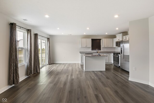 kitchen featuring appliances with stainless steel finishes, sink, a center island with sink, white cabinets, and dark wood-type flooring