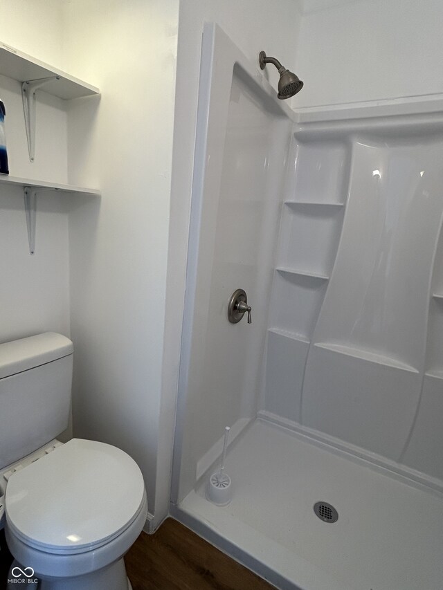 bathroom featuring hardwood / wood-style flooring, toilet, and walk in shower