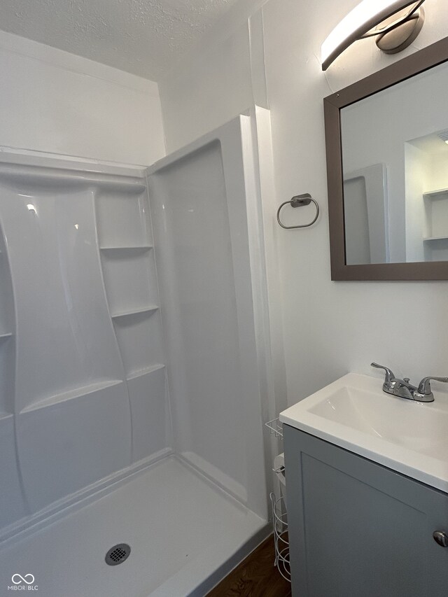 bathroom featuring a textured ceiling, vanity, wood-type flooring, and walk in shower