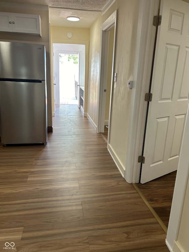 corridor with a textured ceiling and dark wood-type flooring