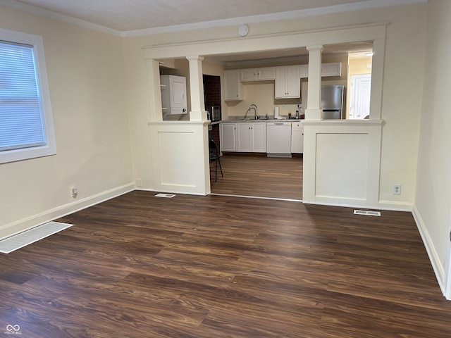 interior space featuring dark hardwood / wood-style flooring, stacked washer / dryer, ornamental molding, and sink