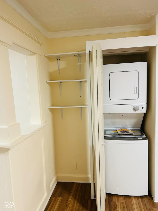 clothes washing area featuring crown molding, wood-type flooring, and stacked washer / drying machine