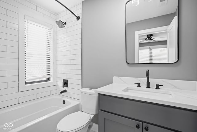 full bathroom with tiled shower / bath, toilet, ceiling fan, and vanity