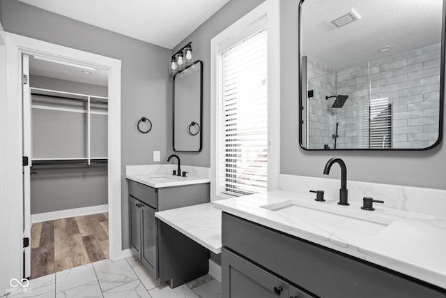 bathroom with tiled shower, hardwood / wood-style floors, and vanity