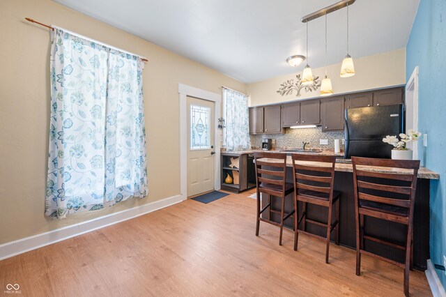 kitchen with light hardwood / wood-style floors, black refrigerator, sink, and backsplash