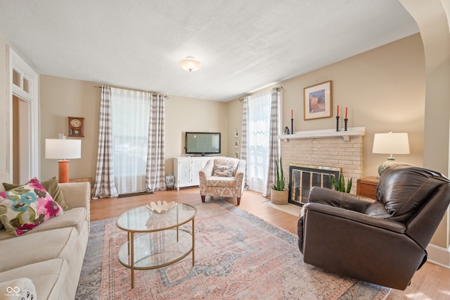 living room featuring a fireplace, a textured ceiling, and light hardwood / wood-style floors