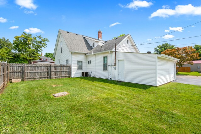 rear view of property with a yard and central AC