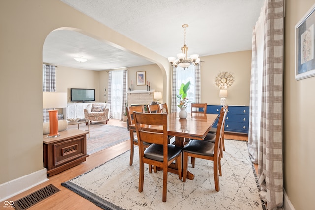 dining space with an inviting chandelier, light hardwood / wood-style flooring, and a textured ceiling