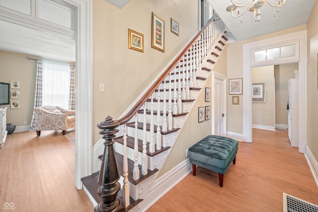 stairway featuring hardwood / wood-style flooring and a notable chandelier