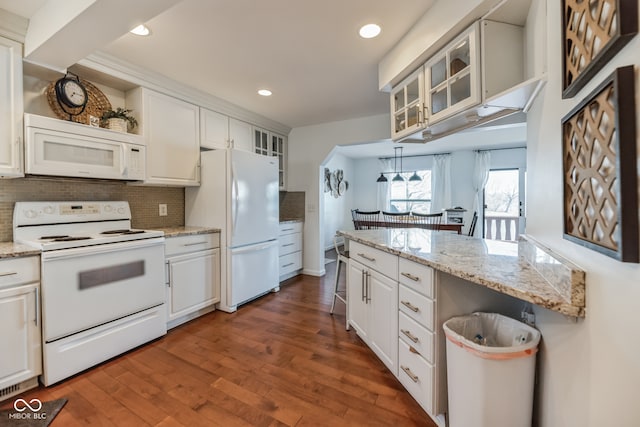 kitchen featuring white cabinets, light stone countertops, backsplash, white appliances, and dark hardwood / wood-style flooring