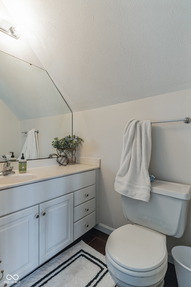 bathroom featuring a textured ceiling, lofted ceiling, toilet, vanity, and tile patterned flooring