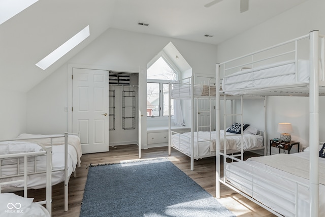 bedroom featuring ceiling fan, vaulted ceiling with skylight, and wood-type flooring