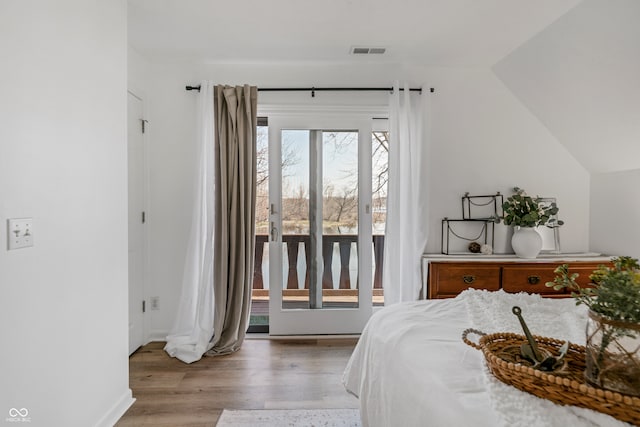 bedroom with access to exterior, hardwood / wood-style floors, and lofted ceiling