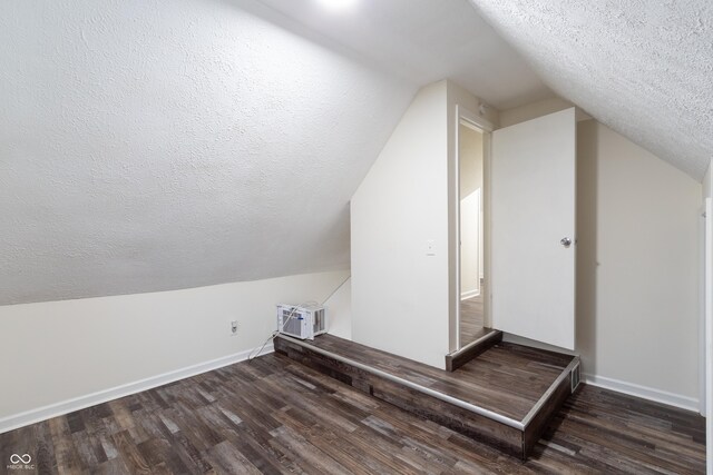 additional living space with wood-type flooring, a textured ceiling, and lofted ceiling