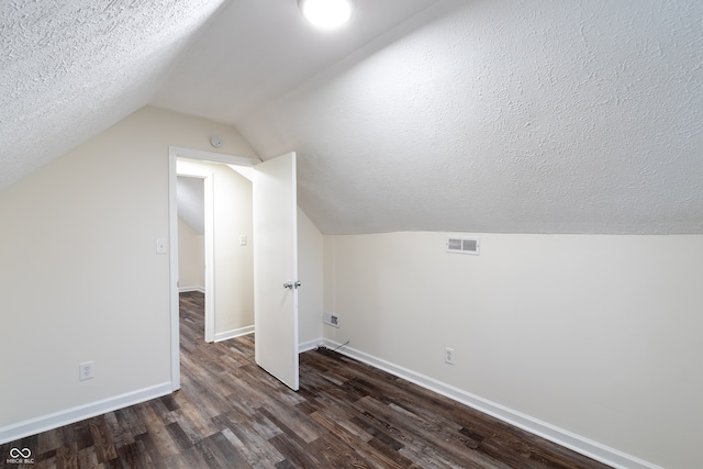 additional living space with a textured ceiling, lofted ceiling, and dark hardwood / wood-style flooring