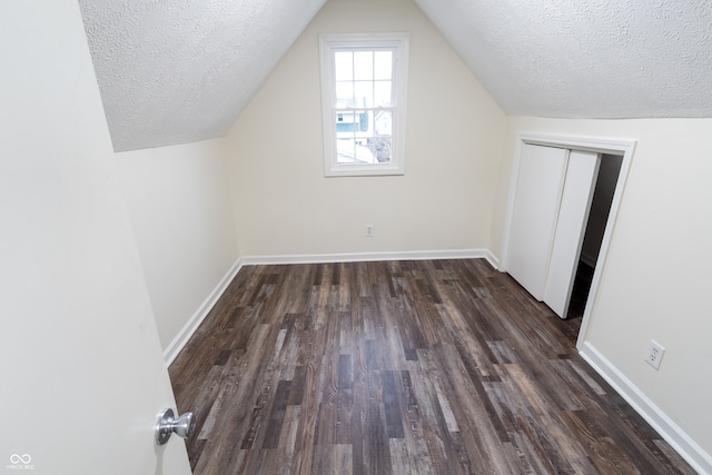 additional living space featuring vaulted ceiling, a textured ceiling, and dark wood-type flooring