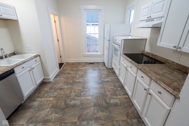 kitchen featuring dark tile patterned flooring, white cabinets, sink, dark stone countertops, and white appliances