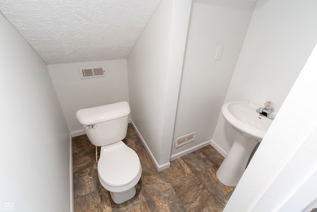 bathroom featuring toilet, a textured ceiling, and lofted ceiling