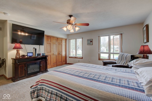 bedroom with a closet, ceiling fan, carpet, and a textured ceiling