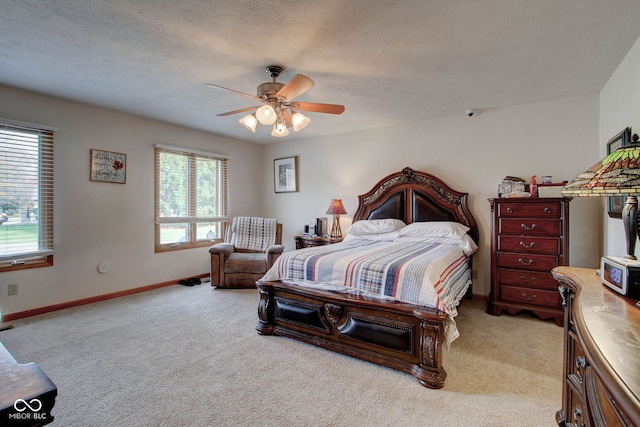 bedroom with ceiling fan, light colored carpet, and a textured ceiling