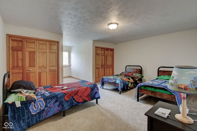 bedroom with two closets, light colored carpet, and a textured ceiling