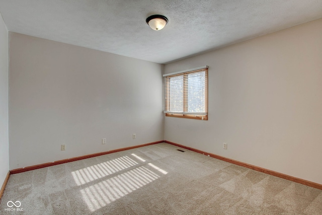 carpeted empty room featuring a textured ceiling