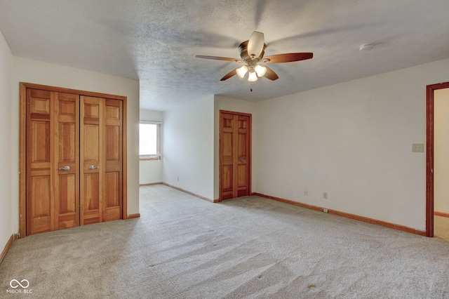 unfurnished bedroom with a textured ceiling, ceiling fan, and light carpet