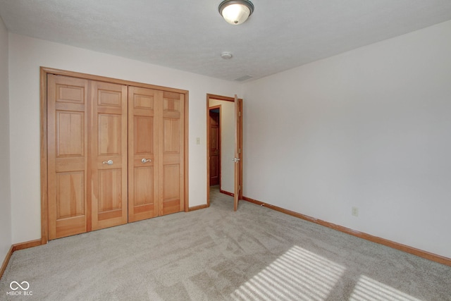 unfurnished bedroom featuring a closet, light colored carpet, and a textured ceiling