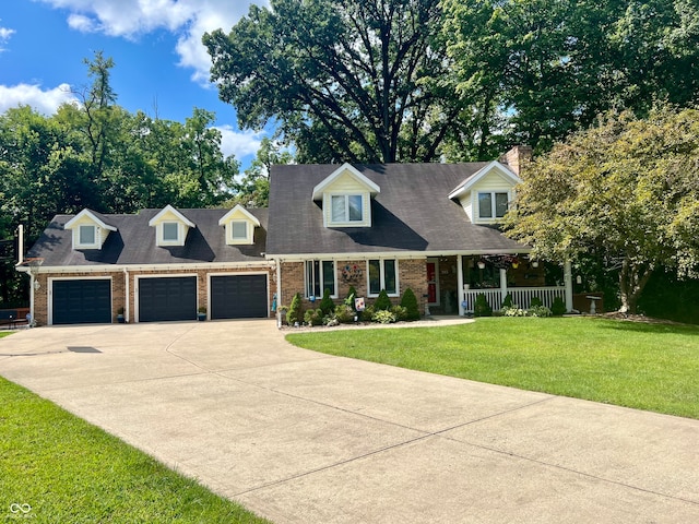 new england style home featuring a garage, a front yard, and covered porch