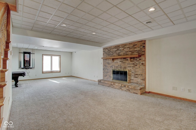 unfurnished living room with a drop ceiling, a brick fireplace, and carpet floors