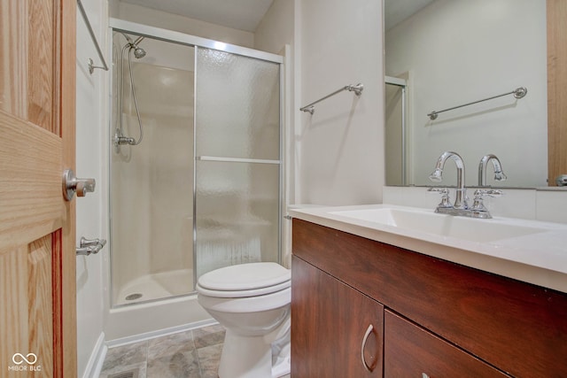 bathroom featuring a shower with door, vanity, and toilet