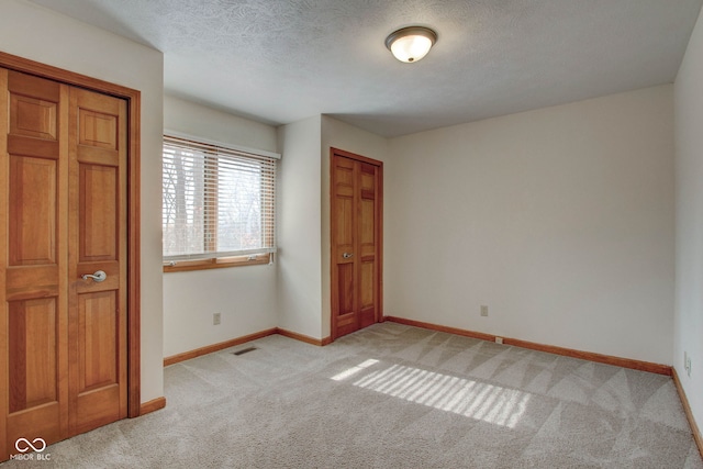 unfurnished bedroom featuring a textured ceiling, light colored carpet, and a closet