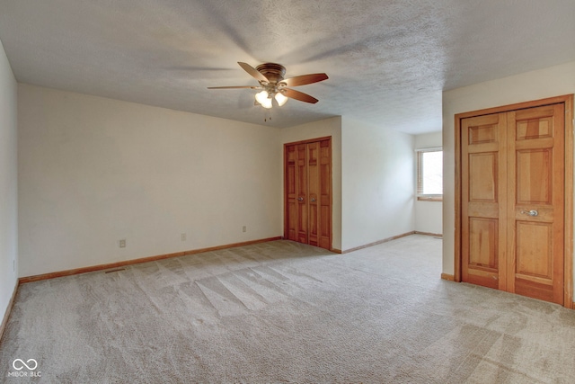 unfurnished bedroom featuring light carpet, a textured ceiling, and ceiling fan