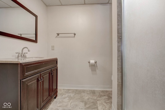 bathroom featuring a shower with door, vanity, and a drop ceiling