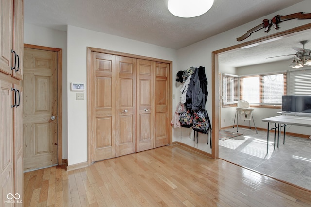 entryway with a textured ceiling, light hardwood / wood-style flooring, and ceiling fan